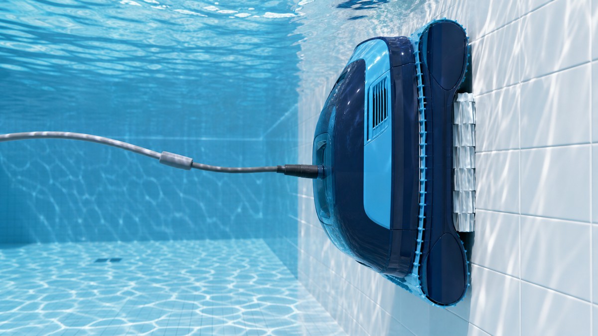 Robot limpiafondos eléctrico Dolphin trepando por la pared interior de una piscina con liner azul