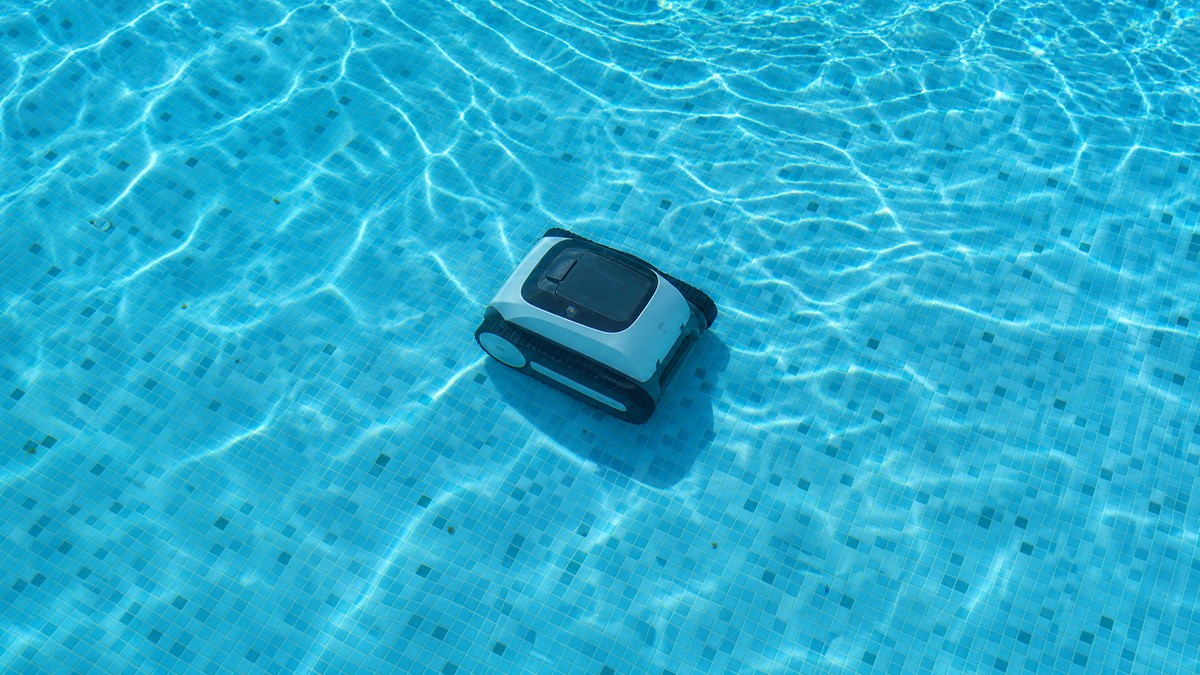 Robot limpiafondos inalámbrico trabajando a mitad de ciclo en una piscina residencial cristalina